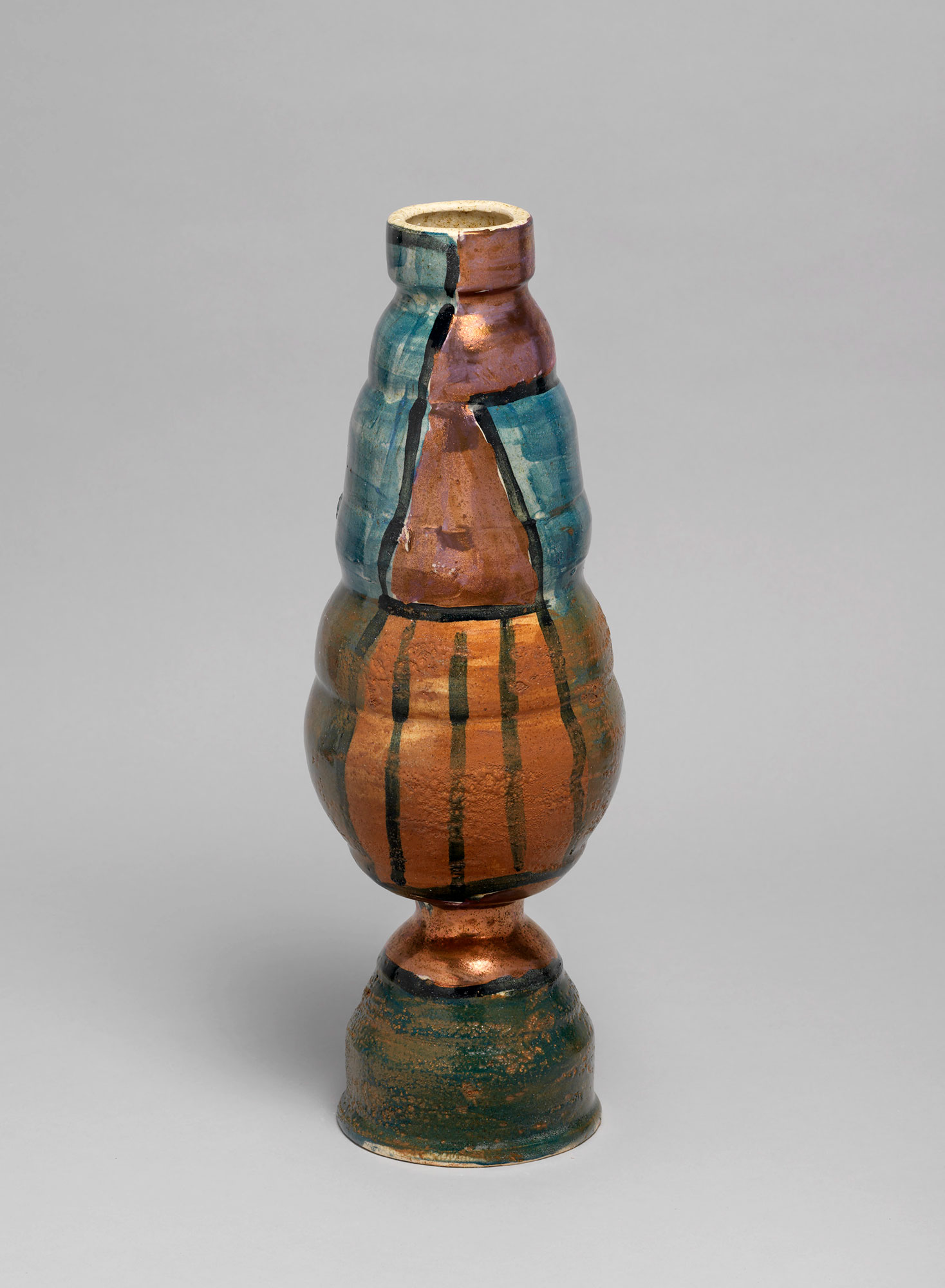 A vase with a base painted dark green, while the body is orange, bronze, turquoise, with black lines separating each color.